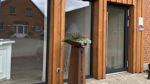 A wooden facade with large glass doors and a welcome sign. - Ferienhof Pankalla (Bassum)