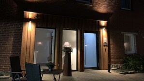 A brick building with a patio area featuring outdoor seating and a potted plant. - Ferienhof Pankalla (Bassum)