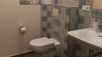 Un baño con inodoro, lavamanos y azulejos con diseño.
