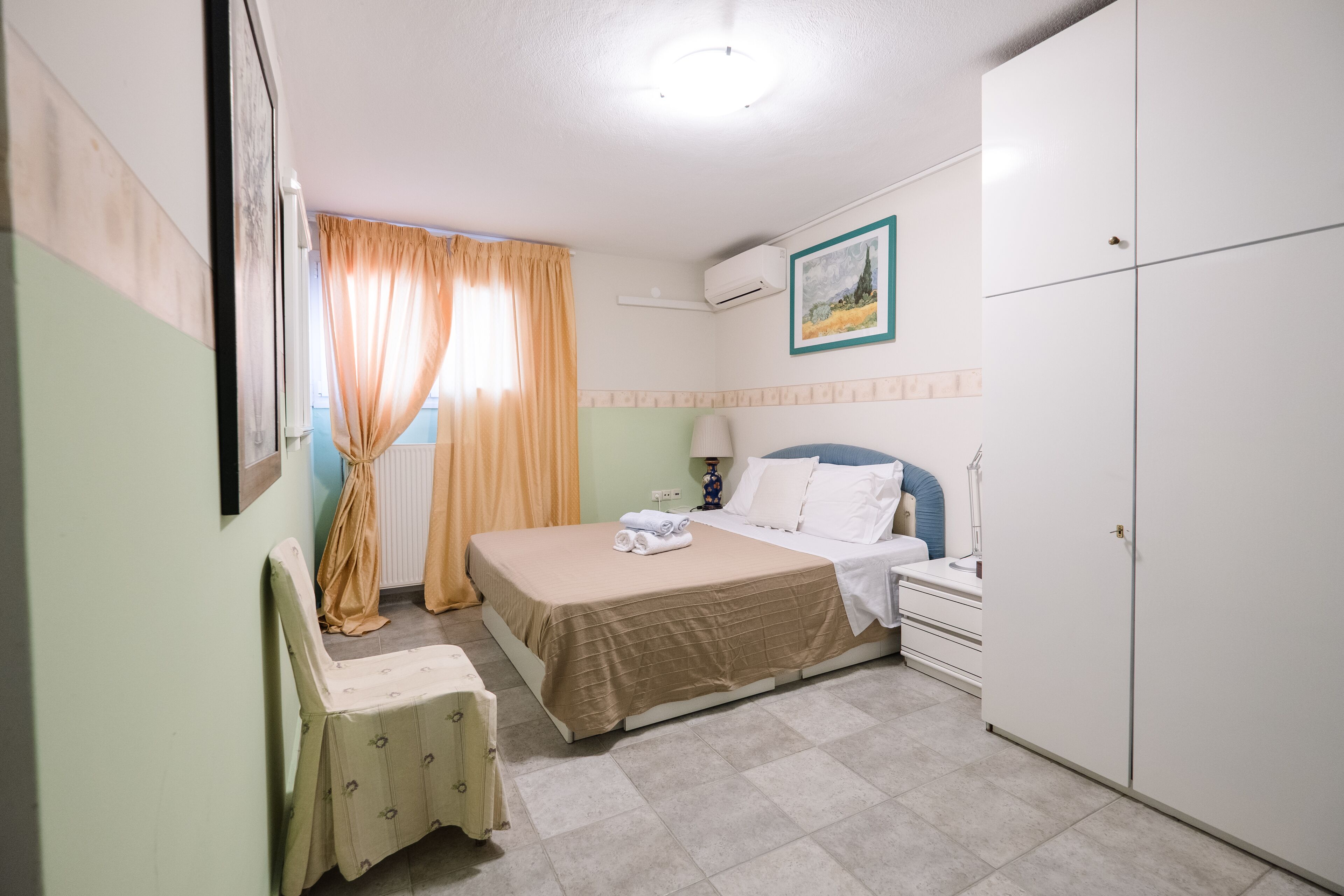 A bedroom with a bed, bedside table, lamp, and wardrobe.