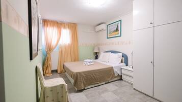 A bedroom with a bed, bedside table, lamp, and wardrobe.