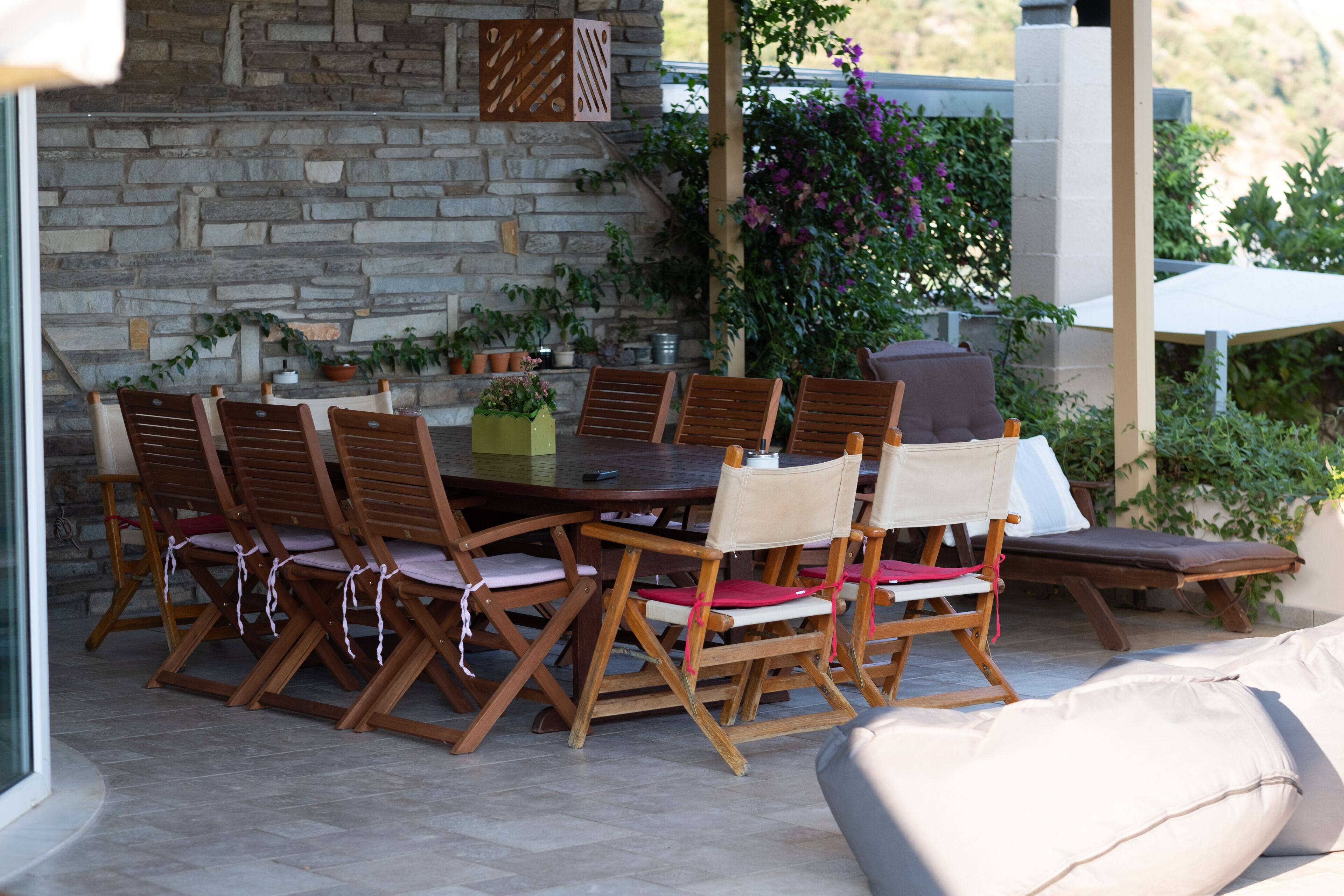 A stone wall, wooden dining table, and chairs with cushions.