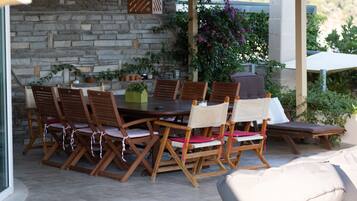 A stone wall, wooden dining table, and chairs with cushions.