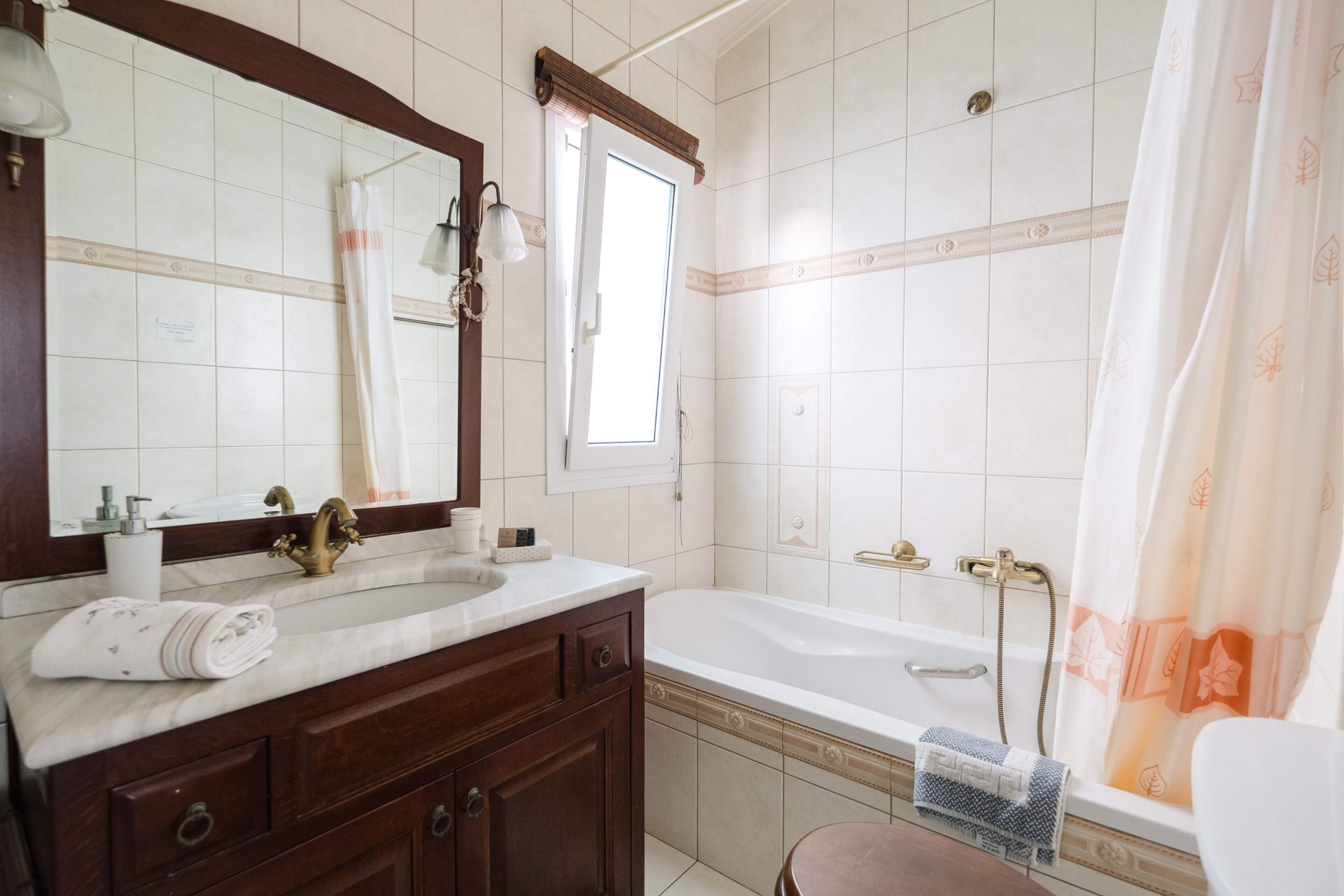A bathroom with a sink, mirror, vanity, bathtub, and shower curtain.