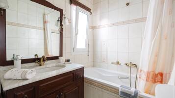 A bathroom with a sink, mirror, vanity, bathtub, and shower curtain.