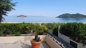 Ein Balkon mit einem Blumentopf, einem Geländer und Blick auf das Meer und vorgelagerte Inseln.