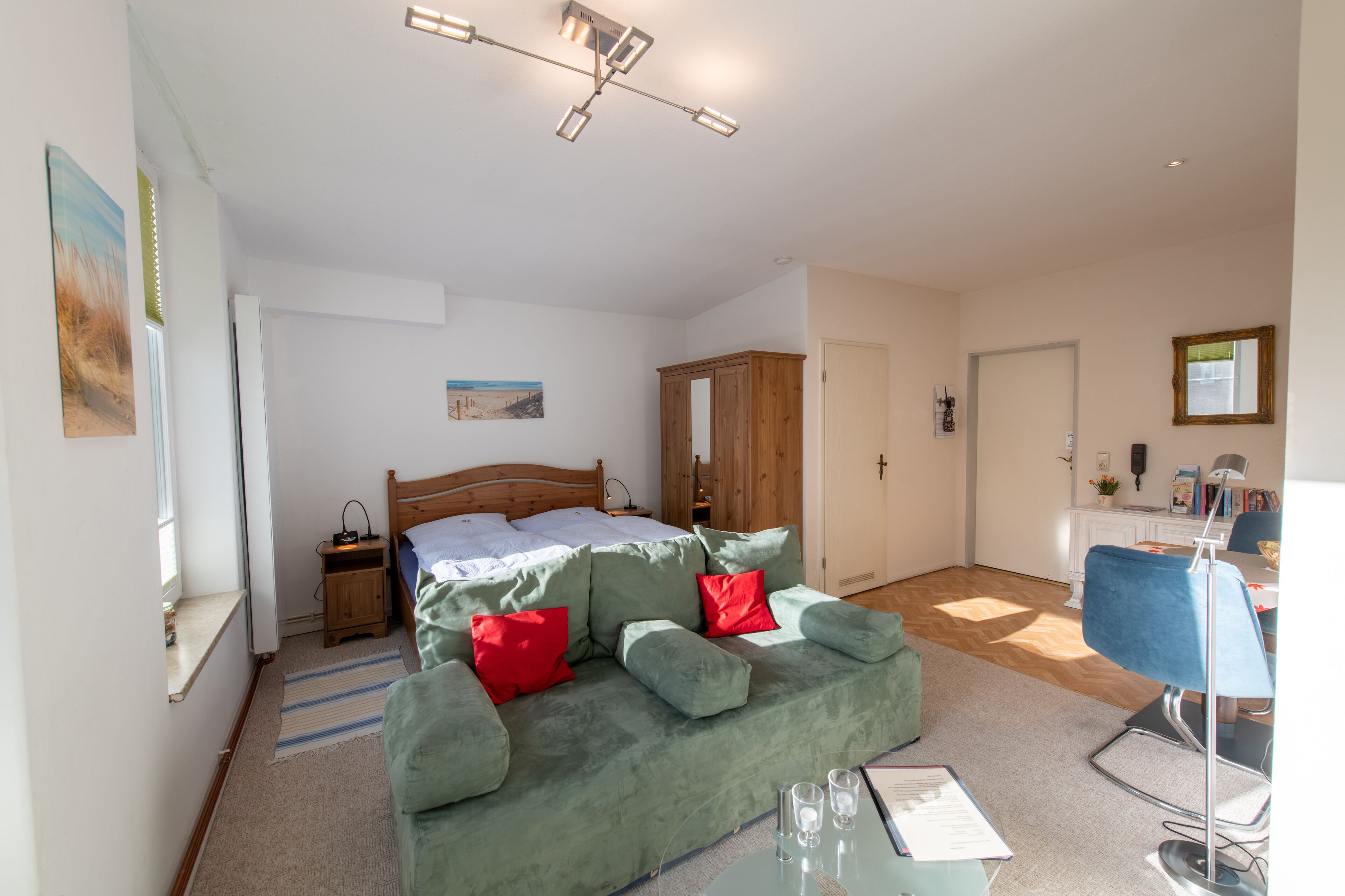 Ein Schlafzimmer mit einem Bett, einem grünen Sofa, einem Schreibtisch und einem Sessel.