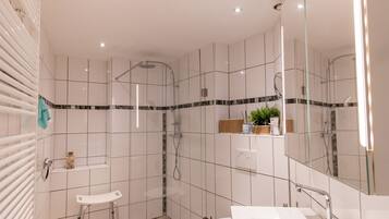 Een moderne badkamer met een douchecabine van glas, een witte wastafel en een toilet.