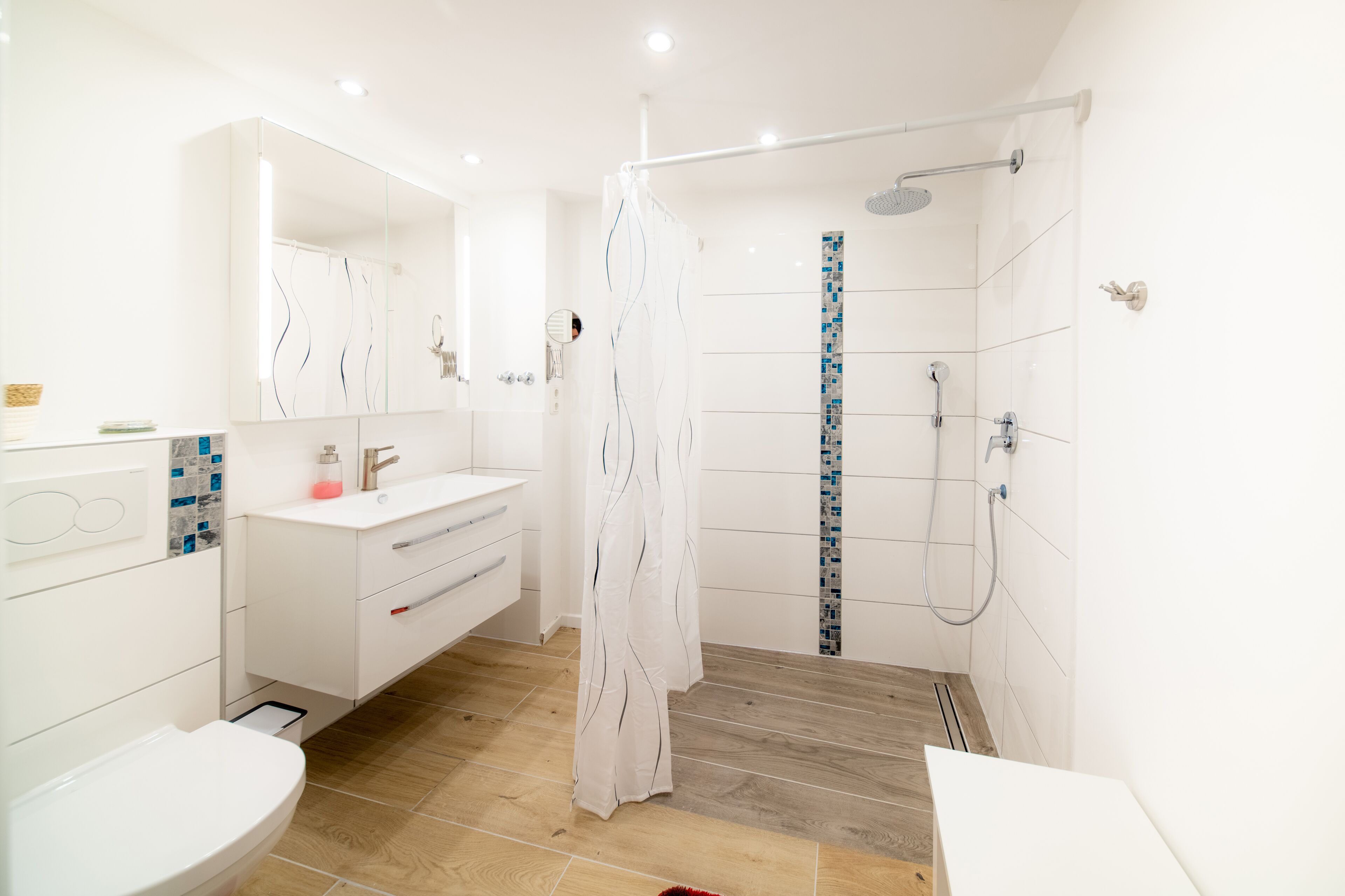 A modern bathroom with a shower, toilet, and vanity.