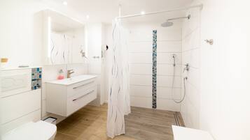 A modern bathroom with a shower, toilet, and vanity.