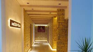 Zona de recepción de un hotel con suelo de mármol, mostrador de recepción y un cartel que indica las habitaciones 106 a 109.