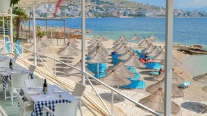 Un restaurante frente al mar con terraza exterior con vistas a la playa y al océano.