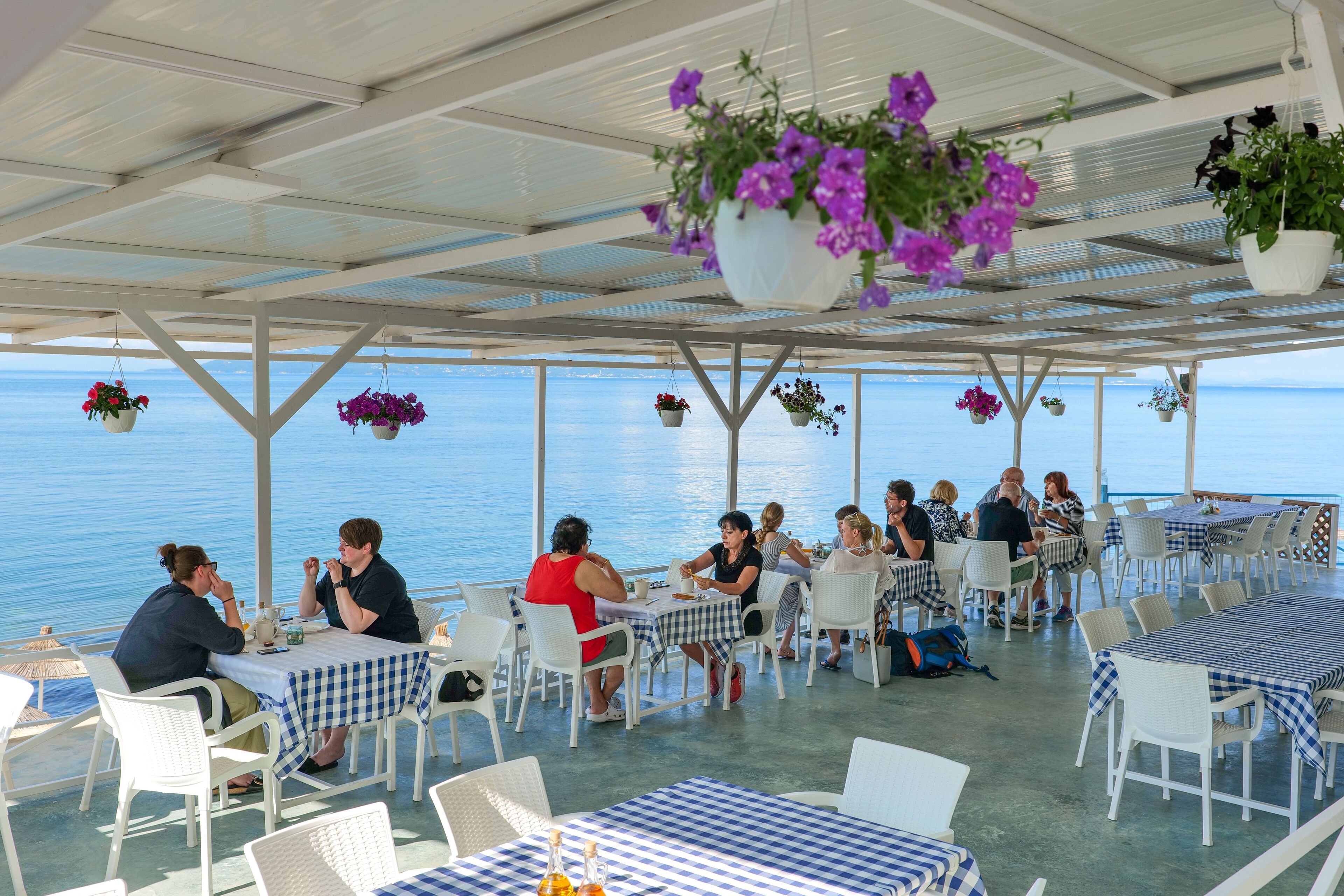 An outdoor dining area with tables and chairs, overlooking a body of water.