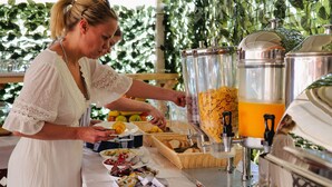 Una barra de buffet con distintos alimentos y un dispensador de bebidas.