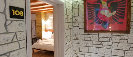 A room with a brick wall, a framed picture of an eagle, and a bed with white bedding.
