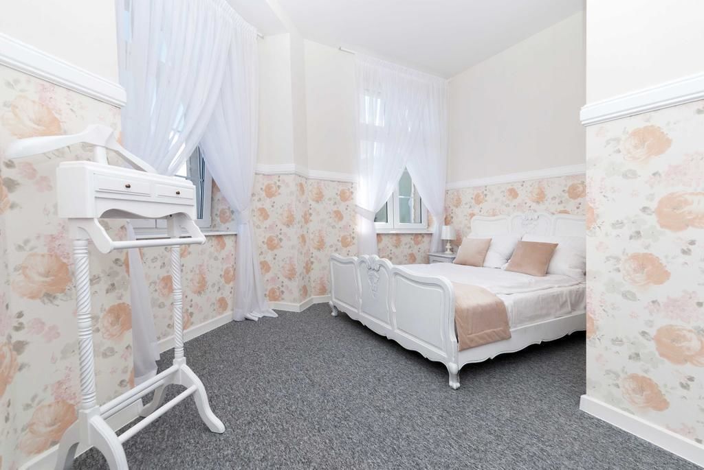 Un dormitorio con cama, mesita de noche, cómoda y ventana con cortinas.