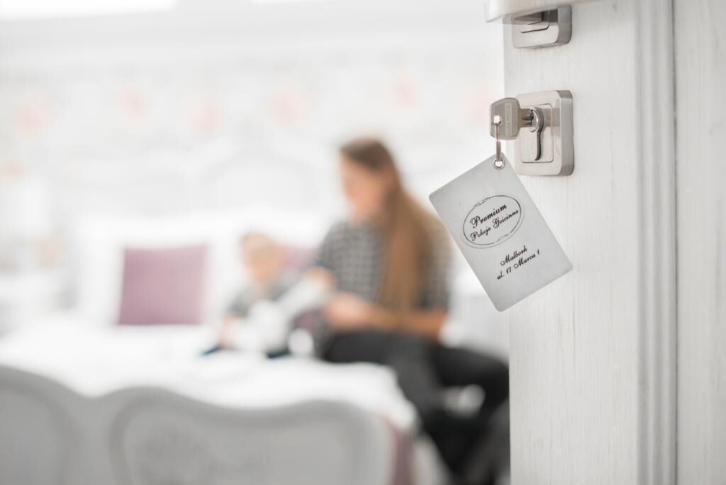 Una habitación de hotel con una cama, una mesita de noche y una puerta con una etiqueta.