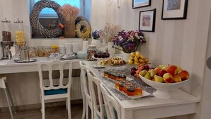 A breakfast setup with a variety of food items, including fruits, pastries, and beverages, arranged on a white table with chairs. - PREMIUM - Bed & Breakfast (Malbork)