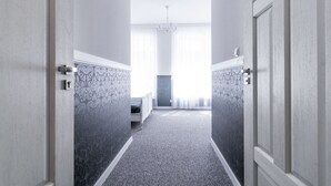 A hallway with a carpeted floor, patterned wallpaper, and a bed at the end. - PREMIUM - Bed & Breakfast (Malbork)