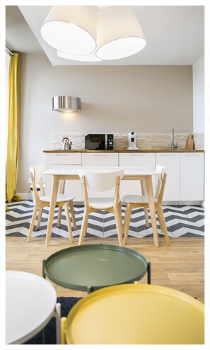 A modern kitchen with white cabinets, a microwave, and a coffee maker. There is a dining table with chairs and a yellow curtain on the left. - Urban Loft & Spa Marseille (Marseille)
