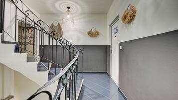 A staircase with a metal railing, a wall-mounted light fixture, and a door with the number '1703' on it.