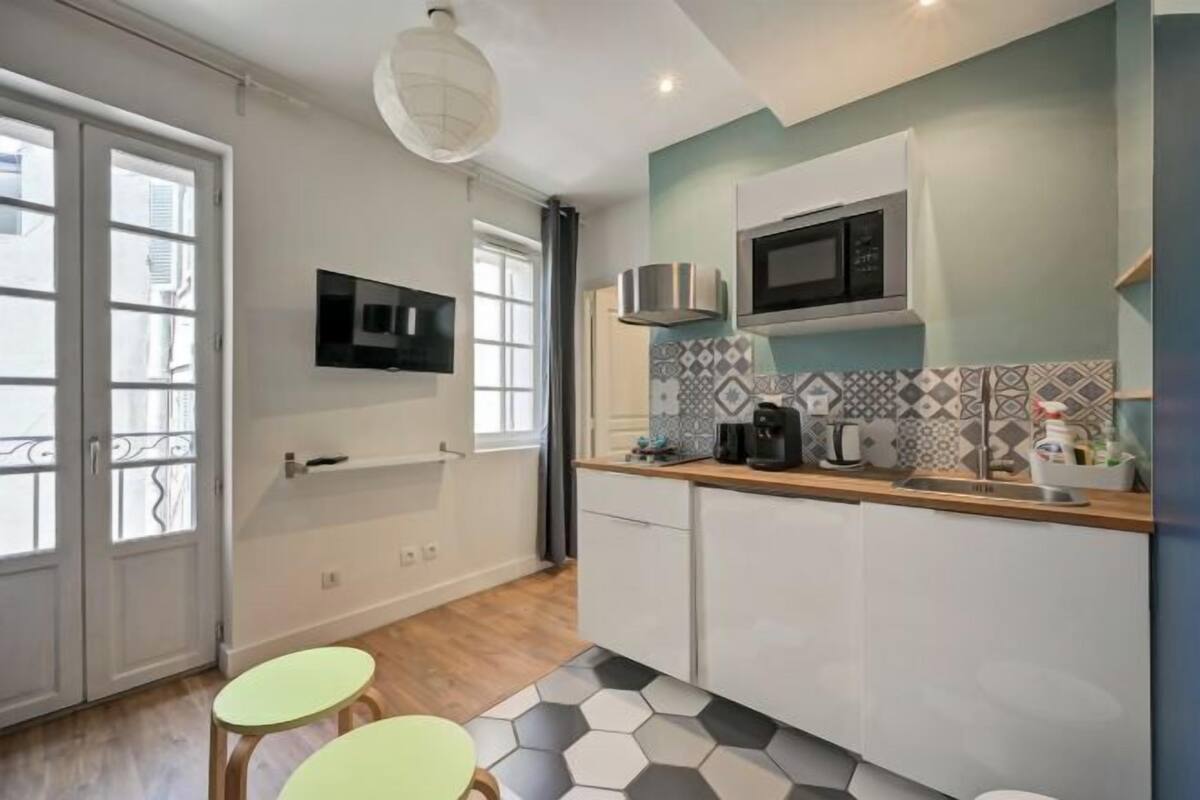 A compact kitchen with a microwave, coffee maker, and a tiled backsplash.
