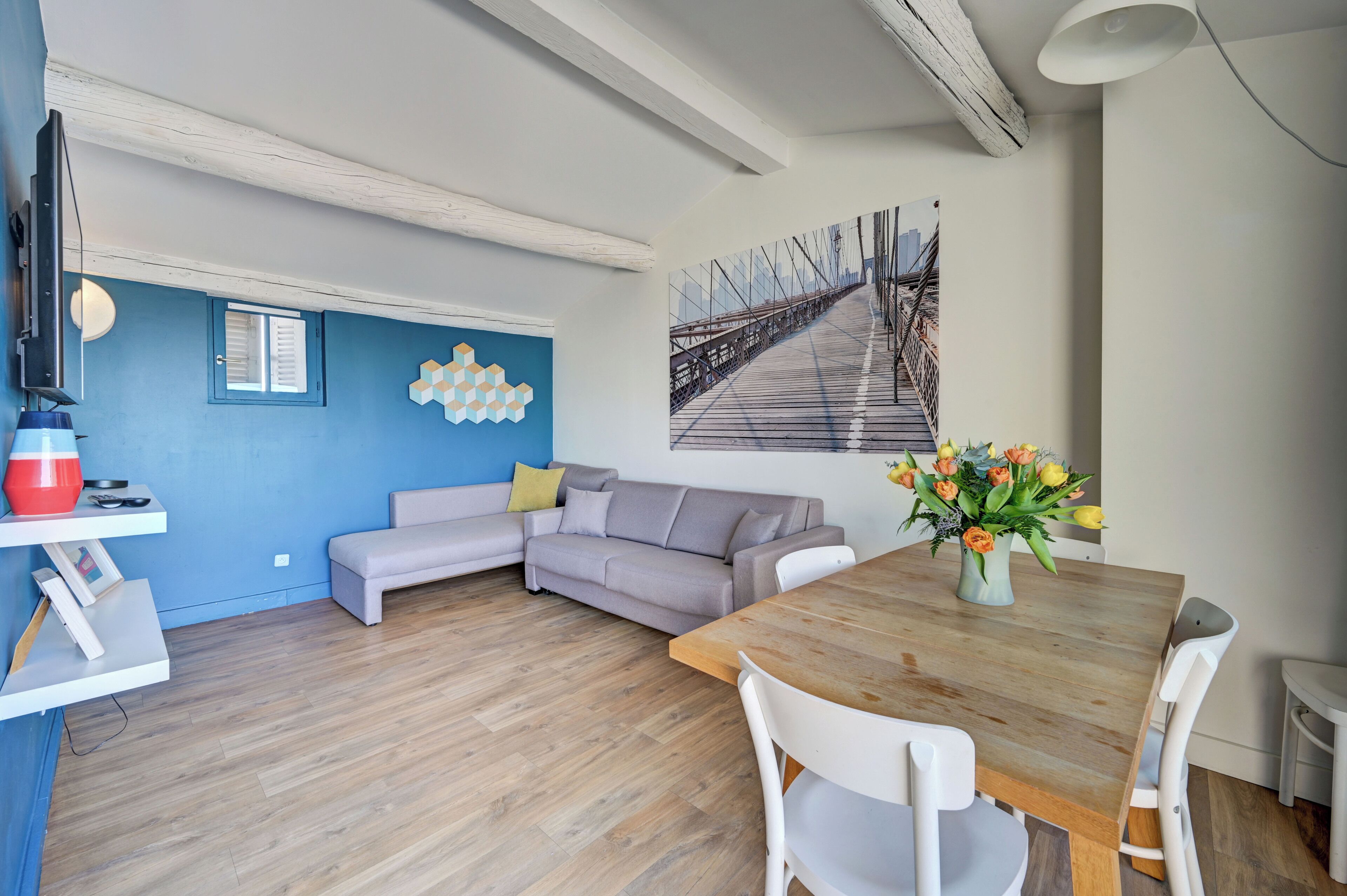 Un salon moderne avec un canapé, une table à manger et un tableau représentant un pont.