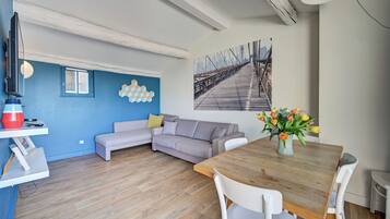 Un salon moderne avec un canapé, une table à manger et un tableau représentant un pont.