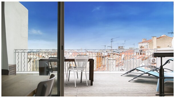 Un balcón con mesa y sillas, con vista a un paisaje urbano con edificios y antenas.
