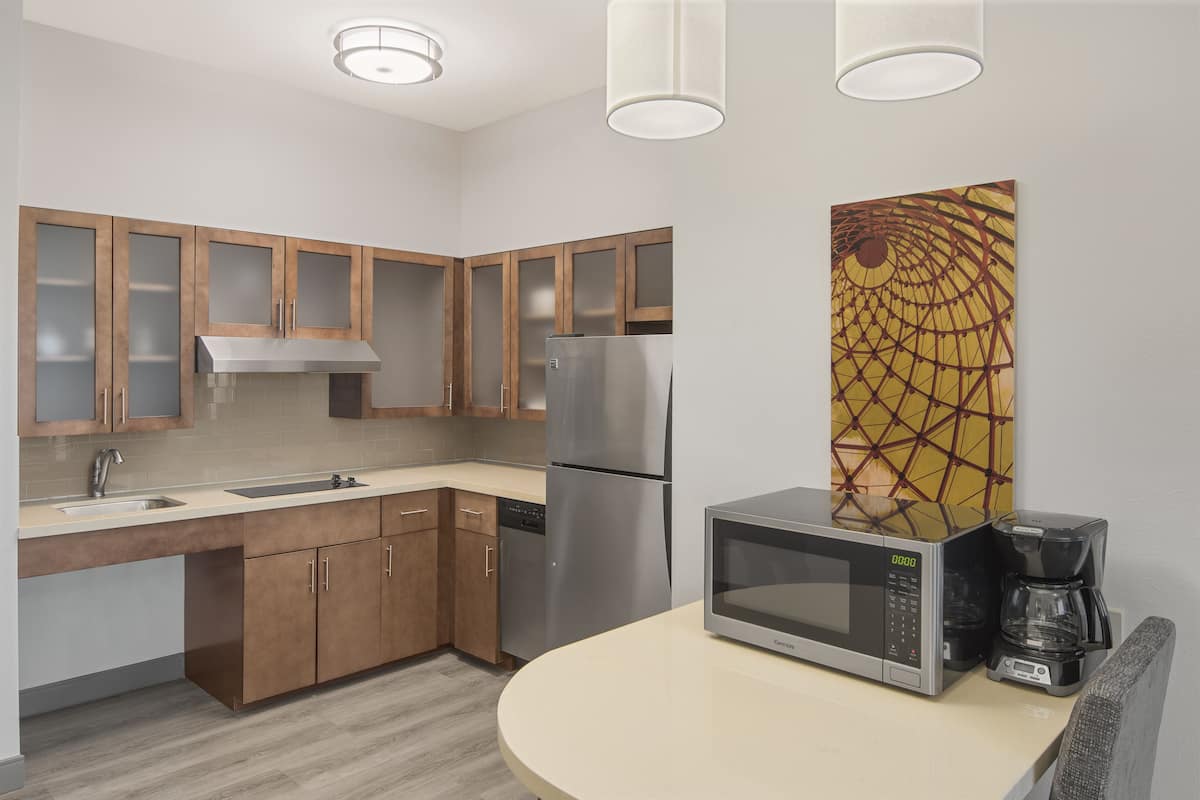 A modern kitchen with wooden cabinets, stainless steel appliances, a microwave, and a coffee maker.
