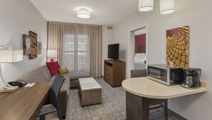 A hotel room with a sofa, a dining table, a coffee maker, a TV, and artwork on the wall. - Staybridge Suites Florence - Civic Center by IHG (Florence)