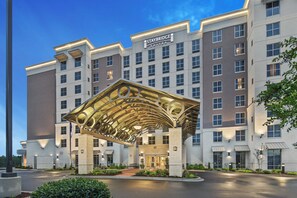 A hotel with a modern architectural design, featuring a prominent entrance canopy and a sign indicating it is a Staybridge Suites hotel.