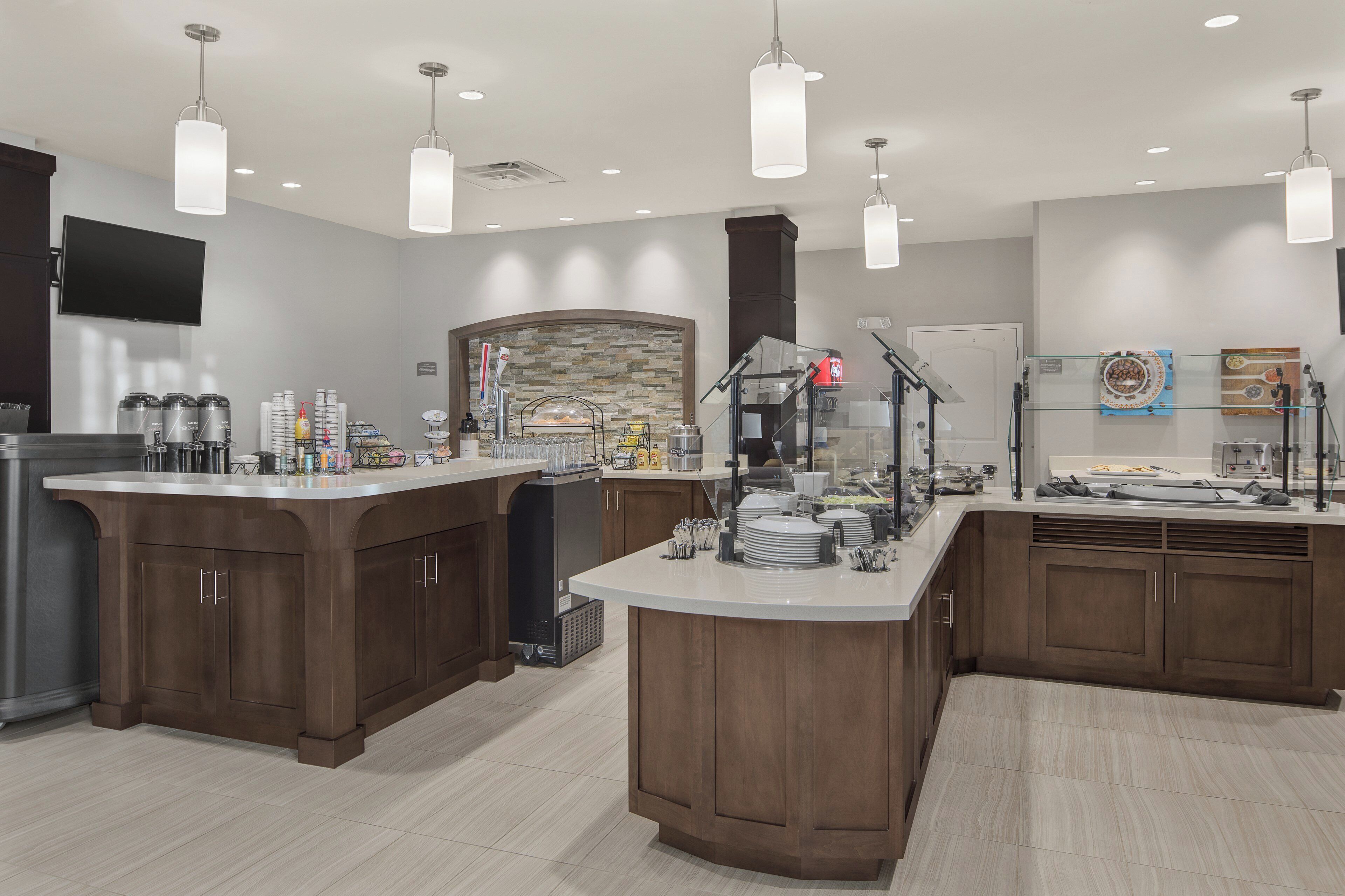 A modern kitchen with a central island, built-in appliances, and a stone backsplash.