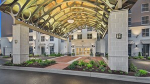 A hotel entrance with a covered walkway, a brick pathway, and a well-maintained garden. - Staybridge Suites Florence - Civic Center by IHG (Florence)