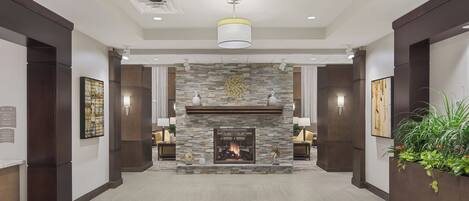 A hotel lobby with a stone fireplace, recessed lighting, and a large plant.
