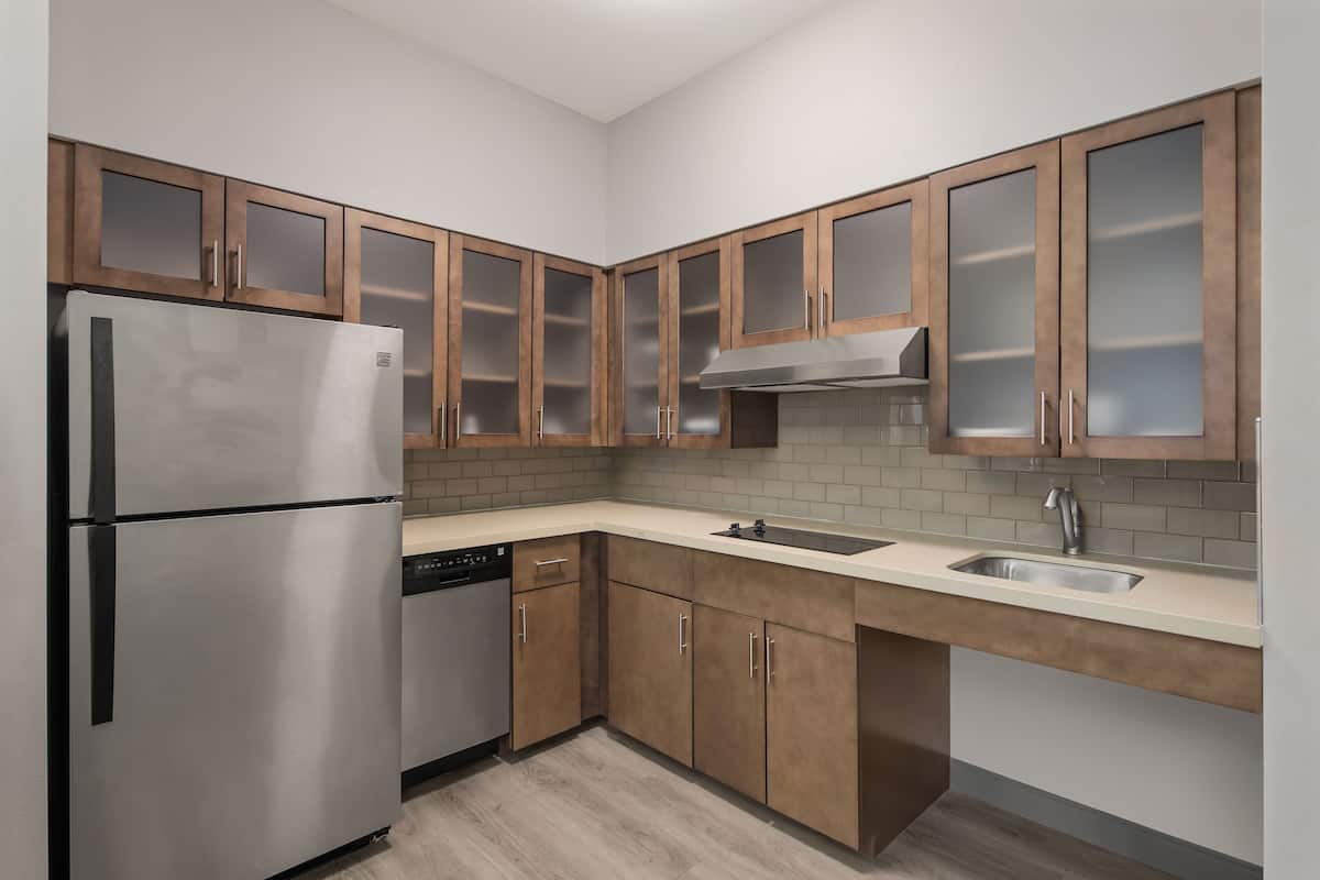 A modern kitchen with wooden cabinets, stainless steel appliances, and a tiled backsplash.