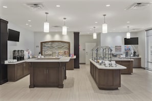 A modern kitchen with two islands, overhead lighting, and a stone backsplash.