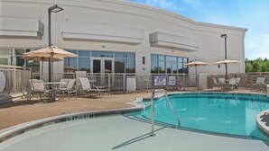 A swimming pool area with lounge chairs and umbrellas, surrounded by a white building with large windows. - Staybridge Suites Florence - Civic Center by IHG (Florence)