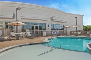 A swimming pool area with lounge chairs and umbrellas, surrounded by a white building with large windows. - Staybridge Suites Florence - Civic Center by IHG (Florence)