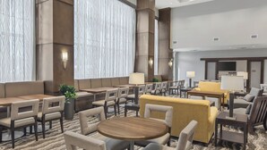A hotel lobby with a seating area, a television, and a reception desk. - Staybridge Suites Florence - Civic Center by IHG (Florence)