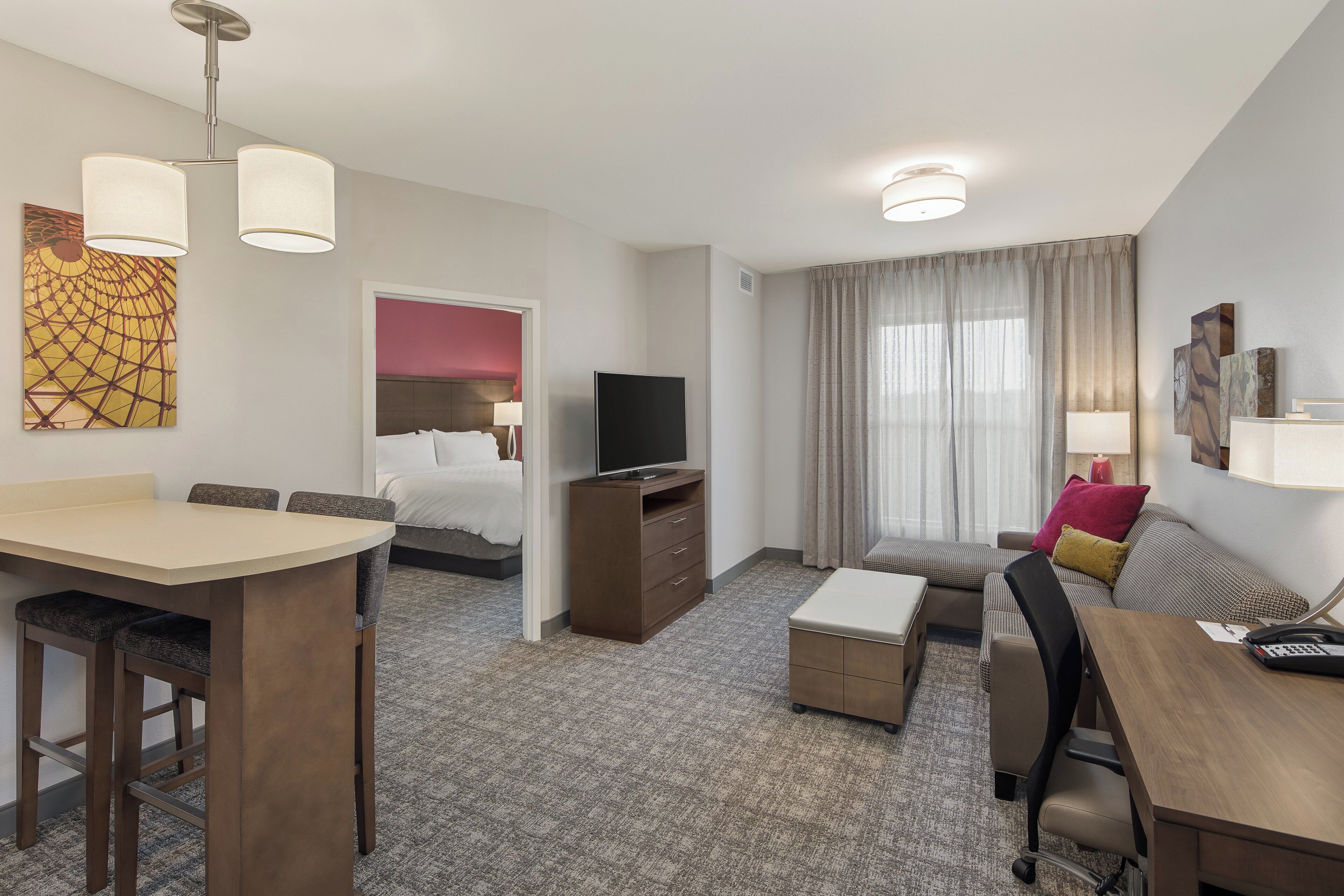 A hotel room with a bed, a TV, a desk, and a sofa.