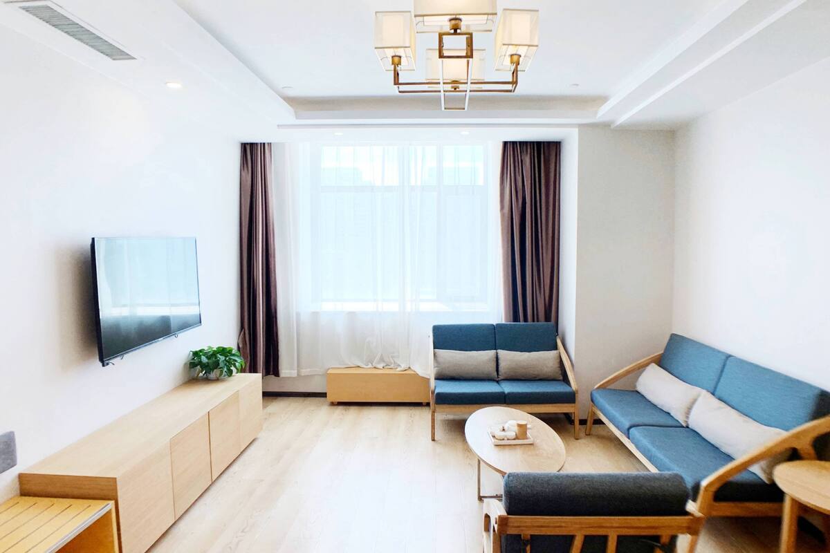 A modern living room with a sofa, a coffee table, a TV, and a plant.