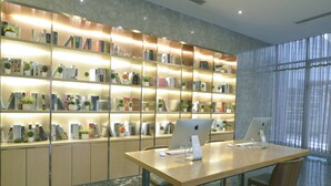 Una biblioteca moderna amb prestatges, dos ordinadors Apple iMac i un taulell de fusta.
