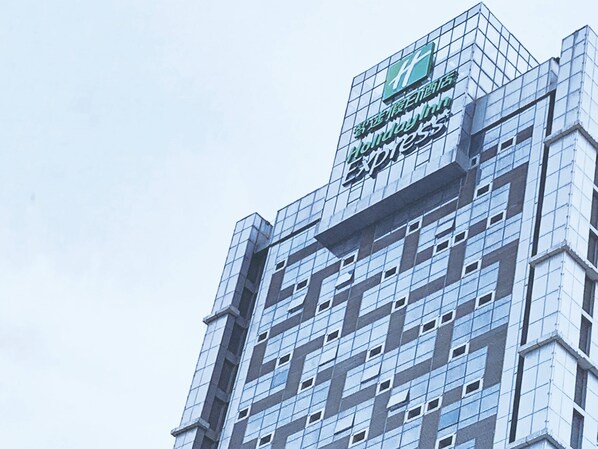 A modern building with a glass facade and a prominent logo at the top. - Holiday Inn Express Jinan Exhibition Center by IHG (Jinan)