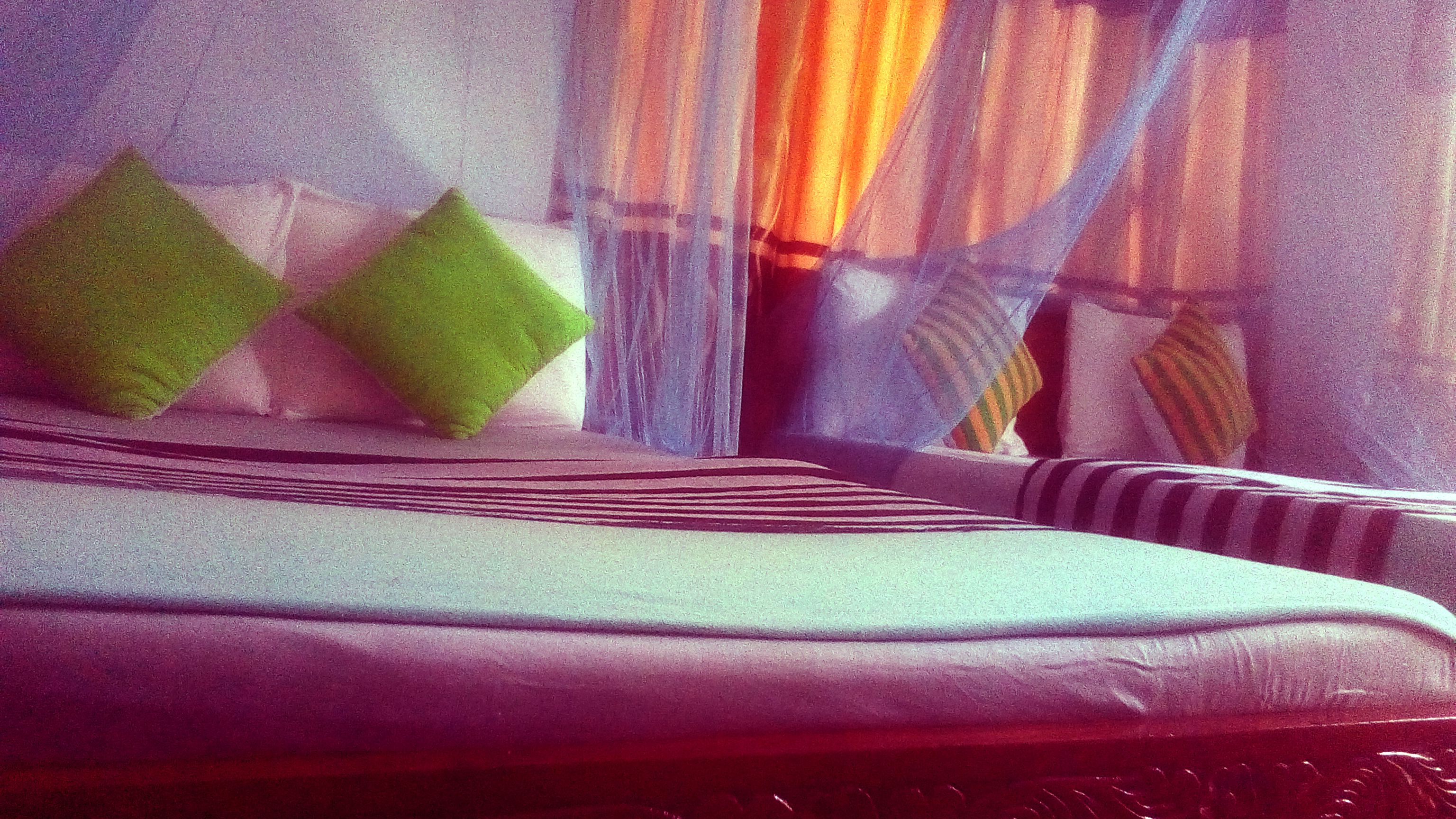 A bed with a striped headboard, green pillows, and a striped blanket.