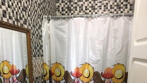 Une salle de bain avec un mur recouvert de carreaux à motifs à carreaux, un lavabo, des toilettes et un rideau de douche orné de personnages de dessins animés.