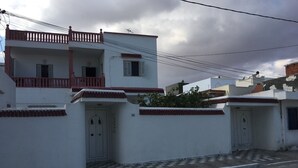 Un bâtiment à deux étages doté d’un balcon, d’un pavage à carreaux et d’une route devant.
