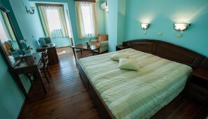 Ein Schlafzimmer mit einem hölzernen Bett, einem Schreibtisch, einem Stuhl und einem Fenster mit Vorhängen.