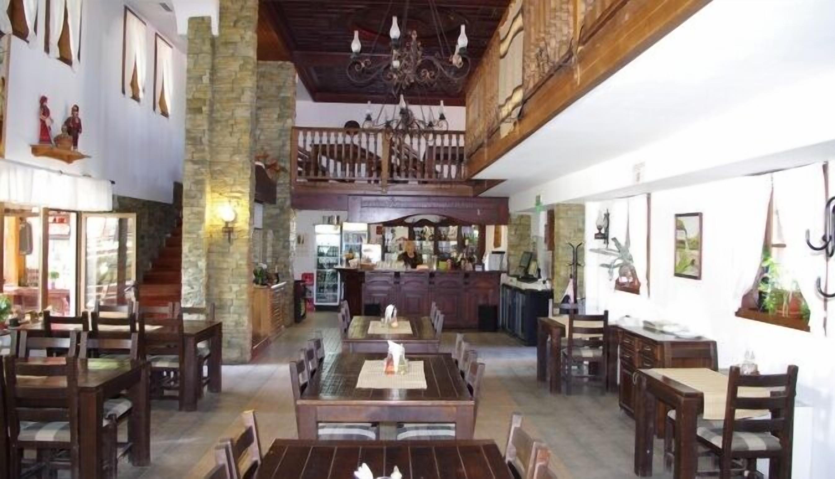 Uma sala de jantar ampla com pé direito alto e um bar ao fundo.