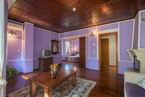 A room with a wooden ceiling, a television, a wooden table with a bottle and glasses, and a bed with a nightstand. - Hotel Izvora (Kranevo)